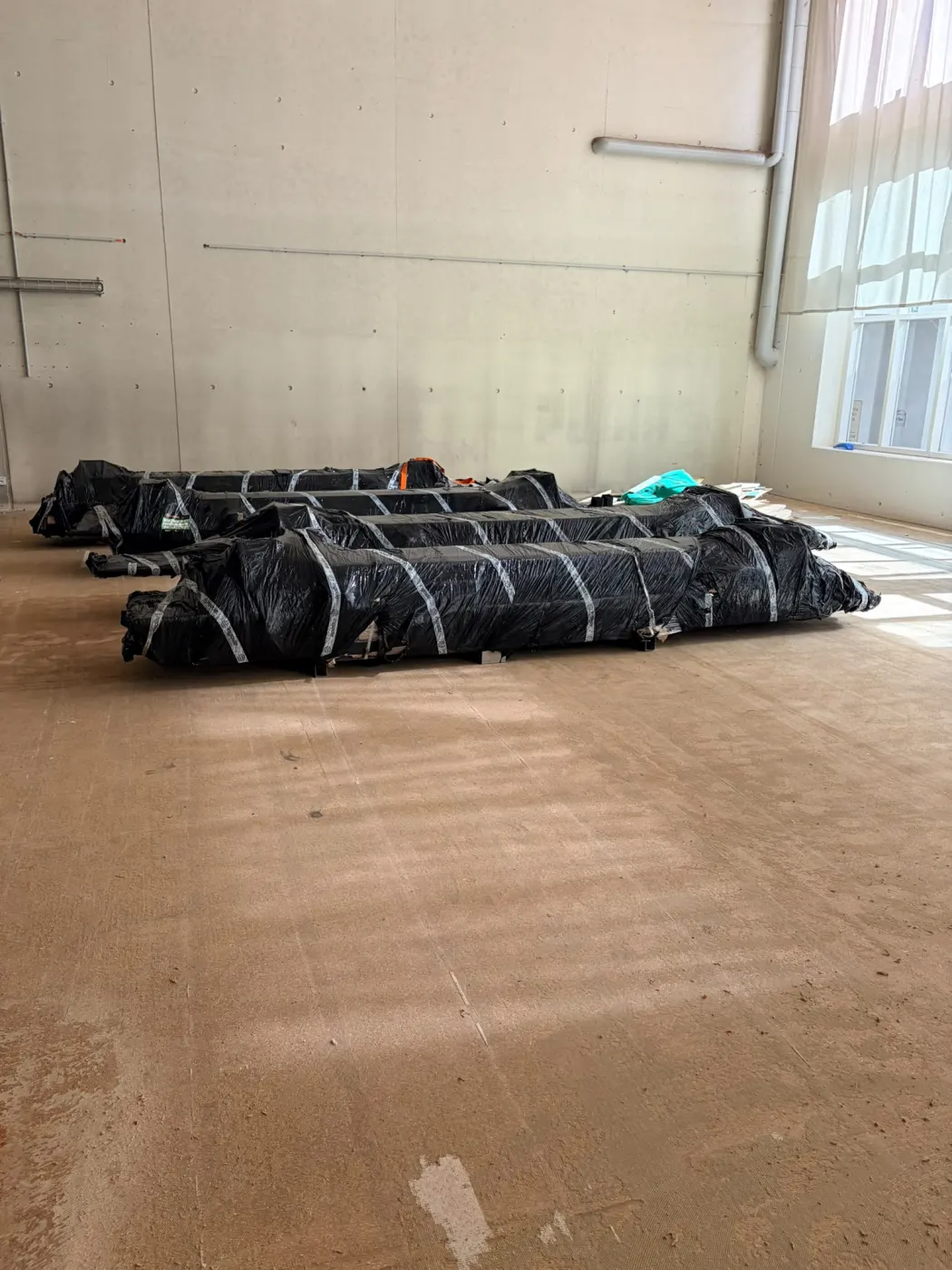 Schwarz verpackte Materialrollen in der leeren Halle